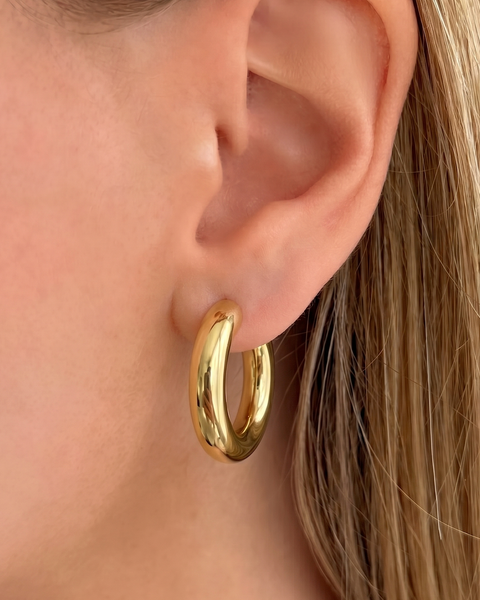 Gold hoop earrings from İrva Collection, featuring a sleek and modern design with a polished finish.
