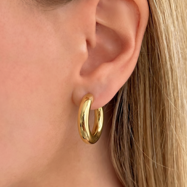 Gold hoop earrings from İrva Collection, featuring a sleek and modern design with a polished finish.
