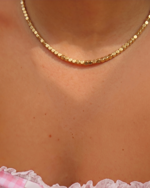 Gold Dorika necklace from İrva Collection featuring intricate design and a delicate chain, displayed against a neutral background.
