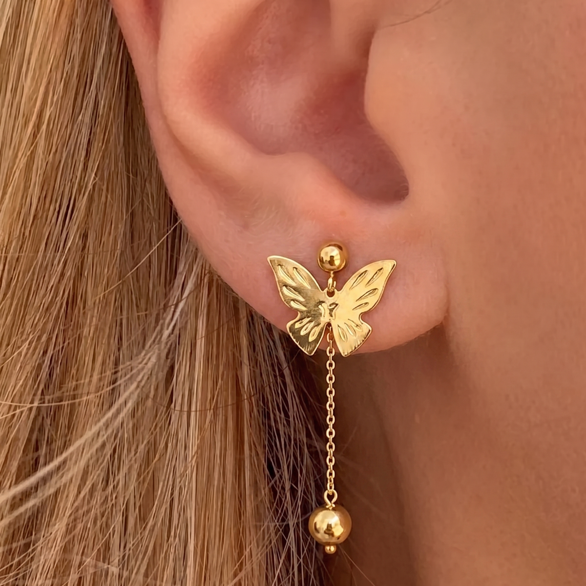 İrva Collection sallantılı kelebek küpe with dangling butterfly design, gold-tone metal, and intricate detailing.
