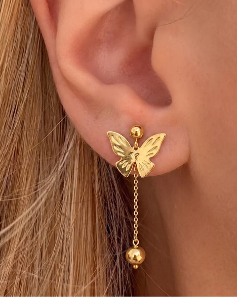 İrva Collection sallantılı kelebek küpe with dangling butterfly design, gold-tone metal, and intricate detailing.