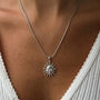 Silver sun pendant necklace from İrva Collection featuring a Gemini symbol, displayed on a neutral background.