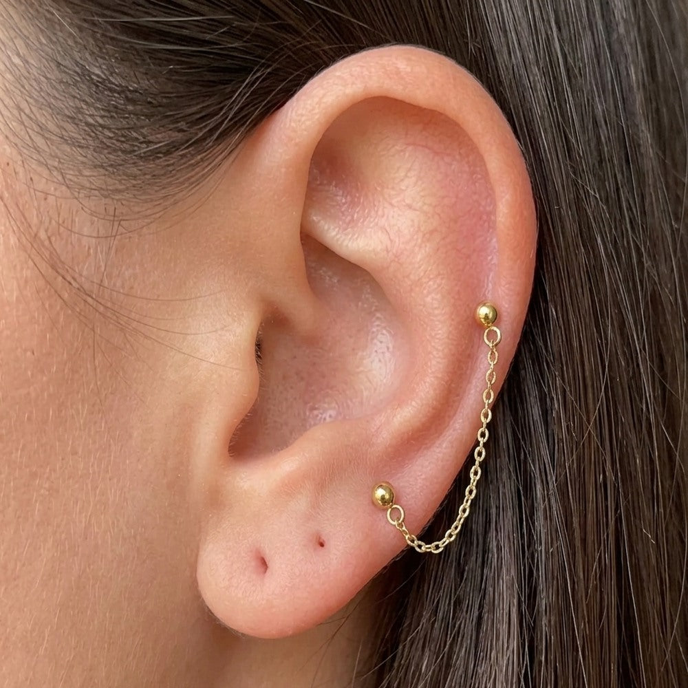 İrva Collection çift delik zincir küpe with dangling Gemini-shaped charms on a white background